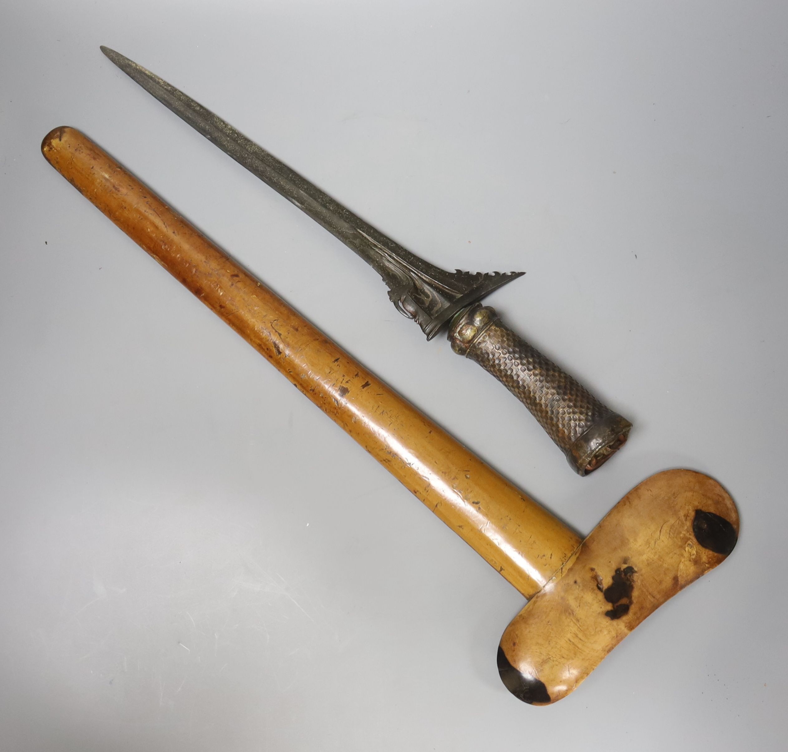 An Indonesian dagger kris, 19th century, earlier black and silver-coloured watered blade, brass hilt, wooden scabbard, blade 33cms